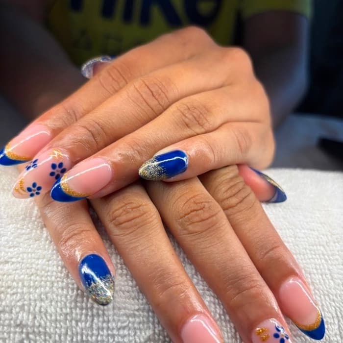 Blue french · gold glitter florals — nails by Ezra's Nail Studio, Aluva