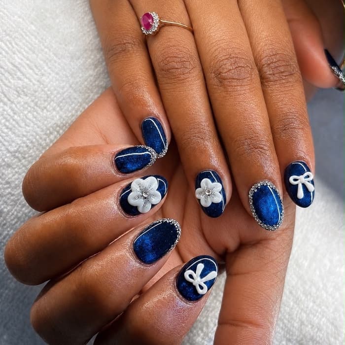 Navy gel · white flowers & bows — nails by Ezra's Nail Studio, Aluva