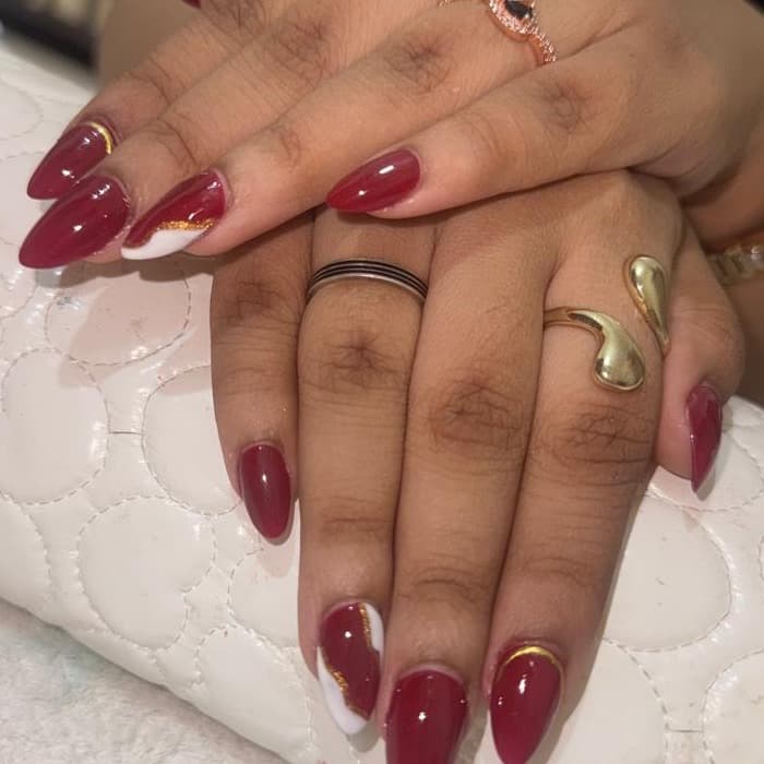 Red gel · white & gold art — nails by Ezra's Nail Studio, Aluva